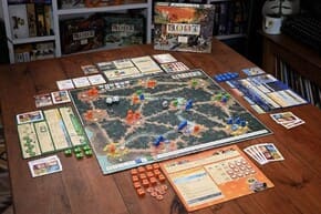 # Root voor Beginners – Een Complete Startgids Root is een strategisch bordspel waarin verschillende facties met hun eigen regels, doelen en speelstijlen strijden om invloed in een uitgestrekt bos. Voor nieuwe spelers kan het spel in het begin behoorlijk uitgebreid lijken. Iedere factie werkt namelijk anders en een goede eerste kennismaking vraagt daarom om wat voorbereiding. Toch wordt Root veel overzichtelijker zodra je begrijpt hoe de belangrijkste onderdelen met elkaar samenhangen. Het eerste wat je moet weten, is dat iedere speler niet simpelweg hetzelfde spel speelt. De basisregels van het bord zijn grotendeels gemeenschappelijk, maar de manier waarop spelers acties uitvoeren en punten verzamelen kan sterk verschillen. Daardoor is het belangrijk om niet alleen naar je eigen mogelijkheden te kijken, maar ook te begrijpen wat andere spelers proberen te bereiken. ## Voorbereiding Voor een eerste partij is het verstandig om voldoende tijd te nemen voor de voorbereiding. Leg het speelbord klaar, bepaal welke facties deelnemen en zorg ervoor dat iedere speler de bijbehorende informatie goed kan bekijken. Nieuwe spelers kunnen het beste beginnen met een factie waarvan de regels relatief gemakkelijk te begrijpen zijn. Tijdens de voorbereiding is het nuttig om vooral aandacht te besteden aan: * de speciale regels van jouw factie; * de manier waarop je overwinningspunten verzamelt; * de beschikbare acties; * de mogelijkheden om te bewegen en te vechten; * de rol van kaarten en andere spelelementen. Probeer niet alle regels van alle facties onmiddellijk uit het hoofd te leren. Dat maakt de eerste partij eerder ingewikkeld dan leuk. ## Hoe verloopt een beurt? Tijdens een partij krijg je verschillende mogelijkheden om je positie te verbeteren. Afhankelijk van je factie kunnen acties bestaan uit bewegen, bouwen, vechten, kaarten gebruiken of andere specifieke handelingen. De volgorde en voorwaarden kunnen per factie verschillen. Een belangrijke beginnersfout is om iedere mogelijke actie meteen te willen gebruiken. In Root is het vaak verstandiger om vooraf te bepalen wat je belangrijkste doel voor de beurt is. Soms levert één goed geplande actie meer op dan meerdere willekeurige acties. ## Kijk naar het hele speelbord Nieuwe spelers concentreren zich vaak volledig op hun eigen gebied. Dat is begrijpelijk, maar Root beloont spelers die ook de plannen van anderen volgen. Kijk regelmatig welke factie groeit, welke gebieden belangrijk worden en welke speler dicht bij een belangrijke mijlpaal komt. Probeer daarnaast vooruit te denken. Vraag jezelf af wat een tegenstander waarschijnlijk tijdens zijn volgende beurt kan doen. Je hoeft niet iedere beweging exact te voorspellen. Het is voldoende om mogelijke risico's te herkennen. ## Eerste strategie Een eenvoudige strategie voor beginners is om eerst stabiliteit op te bouwen. Probeer niet onmiddellijk overal invloed te krijgen. Kies een duidelijke richting en leer hoe jouw factie daar voordeel uit kan halen. Let vooral op deze punten: 1. Houd je belangrijkste gebieden goed in de gaten. 2. Verspil geen acties zonder duidelijk doel. 3. Leer de mogelijkheden van je eigen factie kennen. 4. Observeer voortdurend de voortgang van tegenstanders. 5. Pas je plannen aan wanneer de situatie verandert. Een partij Root is geen vaststaand schema. Je begint met een plan, maar moet bereid zijn dat plan aan te passen wanneer andere spelers onverwachte beslissingen nemen. ## Veel plezier tijdens de eerste partijen De eerste partij hoeft niet perfect te verlopen. Het is normaal dat je regels vergeet, verkeerde keuzes maakt of pas achteraf ontdekt welke actie sterker was geweest. Juist door te spelen leer je hoe verschillende onderdelen met elkaar verbonden zijn. Na enkele partijen wordt het speelbord steeds herkenbaarder. Je begint mogelijkheden eerder te zien en begrijpt beter waarom bepaalde acties belangrijk zijn. Vanaf dat moment komt de strategische diepgang van Root steeds sterker naar voren. Het belangrijkste advies voor beginners is daarom eenvoudig: probeer niet alles tegelijk te beheersen. Leer eerst jouw factie kennen, observeer de andere spelers en ontdek stap voor stap hoe het bos verandert tijdens een partij.